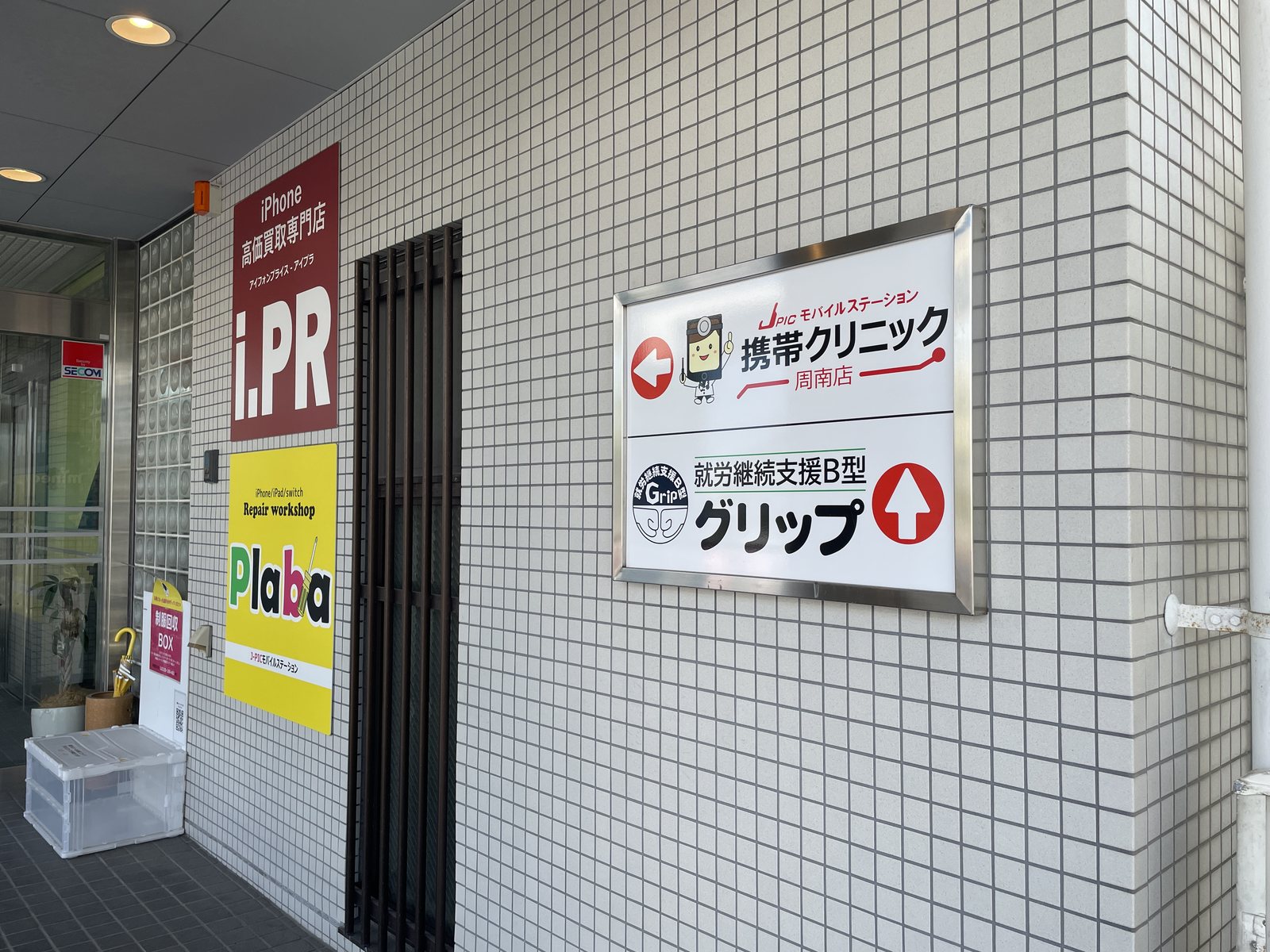 建物の入口にある、携帯クリニックとグリップの案内板
