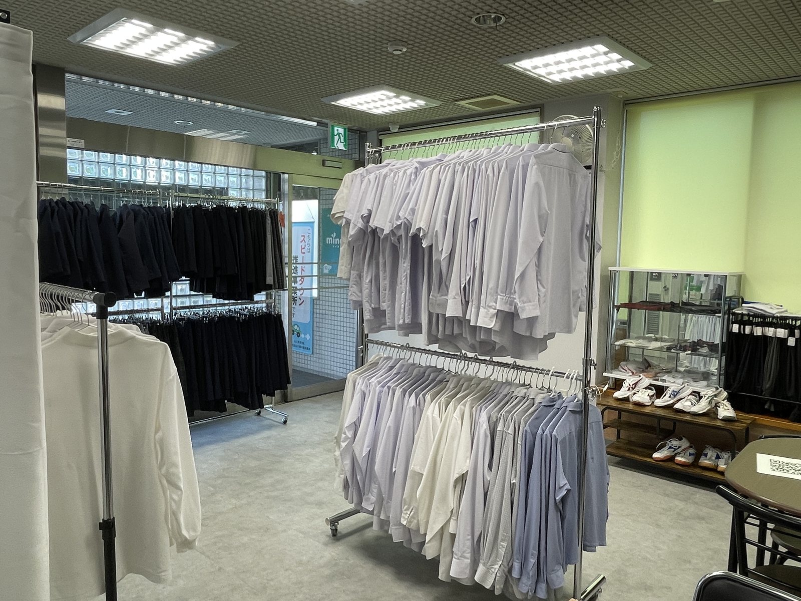 制服リユースの売場。サイズ別にシャツやズボンを掛けている