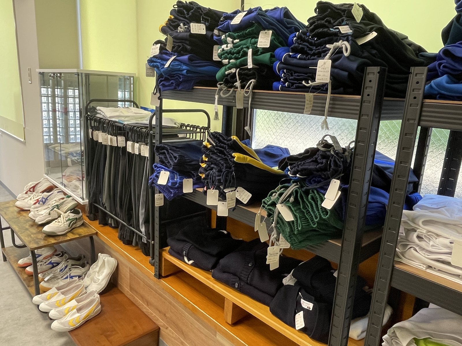 制服リユースの売場の棚。体操服や上履きが並んでいる